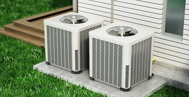 Two heat pumps on top of a concrete slab.