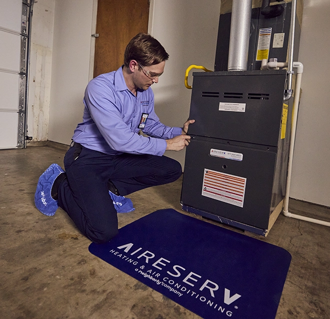 Aire Serv Professional working on a furnace in a clients home.