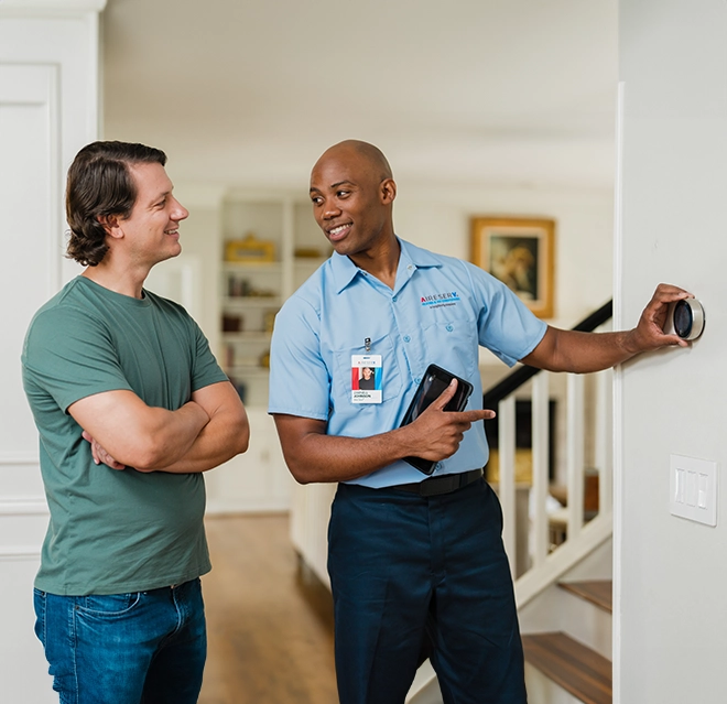 Aire Serv professional talking with a client about the problems with the thermostat.