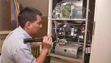 Technician inspecting damaged furnace