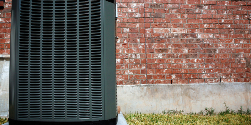 AC condenser unit in front of brick wall
