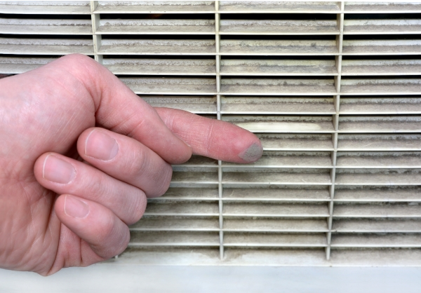 Person wiping finer across a dirt air vent, with dust visible on finger.