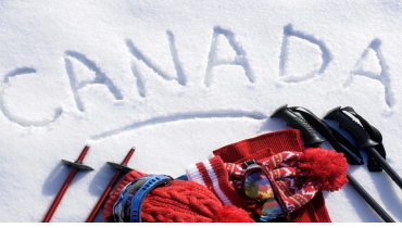 The word ‘Canada’ written in snow next to ski equipment.