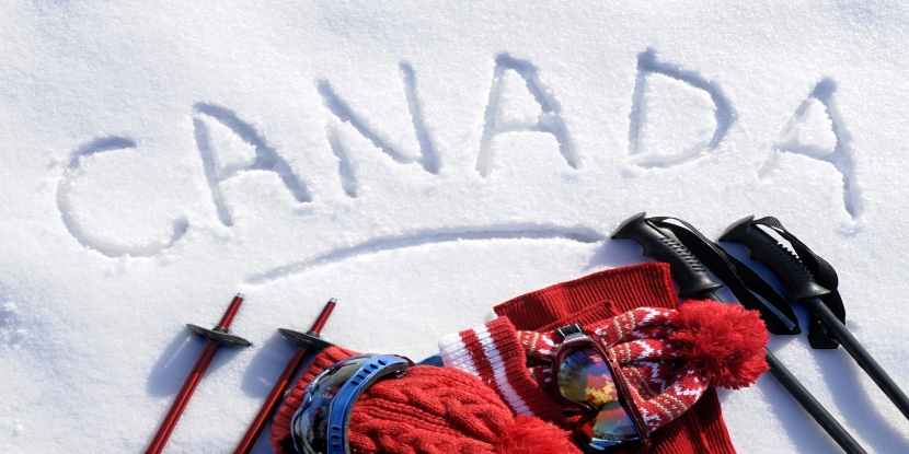 The word ‘Canada’ written in snow next to ski equipment.