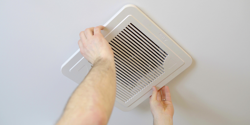 Hands removing air vent in ceiling