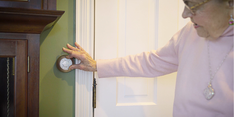 Elderly woman adjusting thermostat
