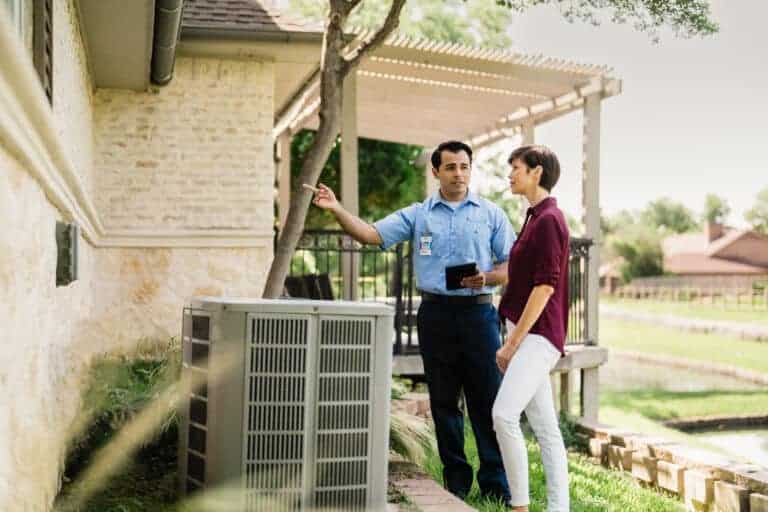 Trusted emergency HVAC repair professional talking with home owner.