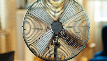 Close-up of metal standing floor fan in bright interior.
